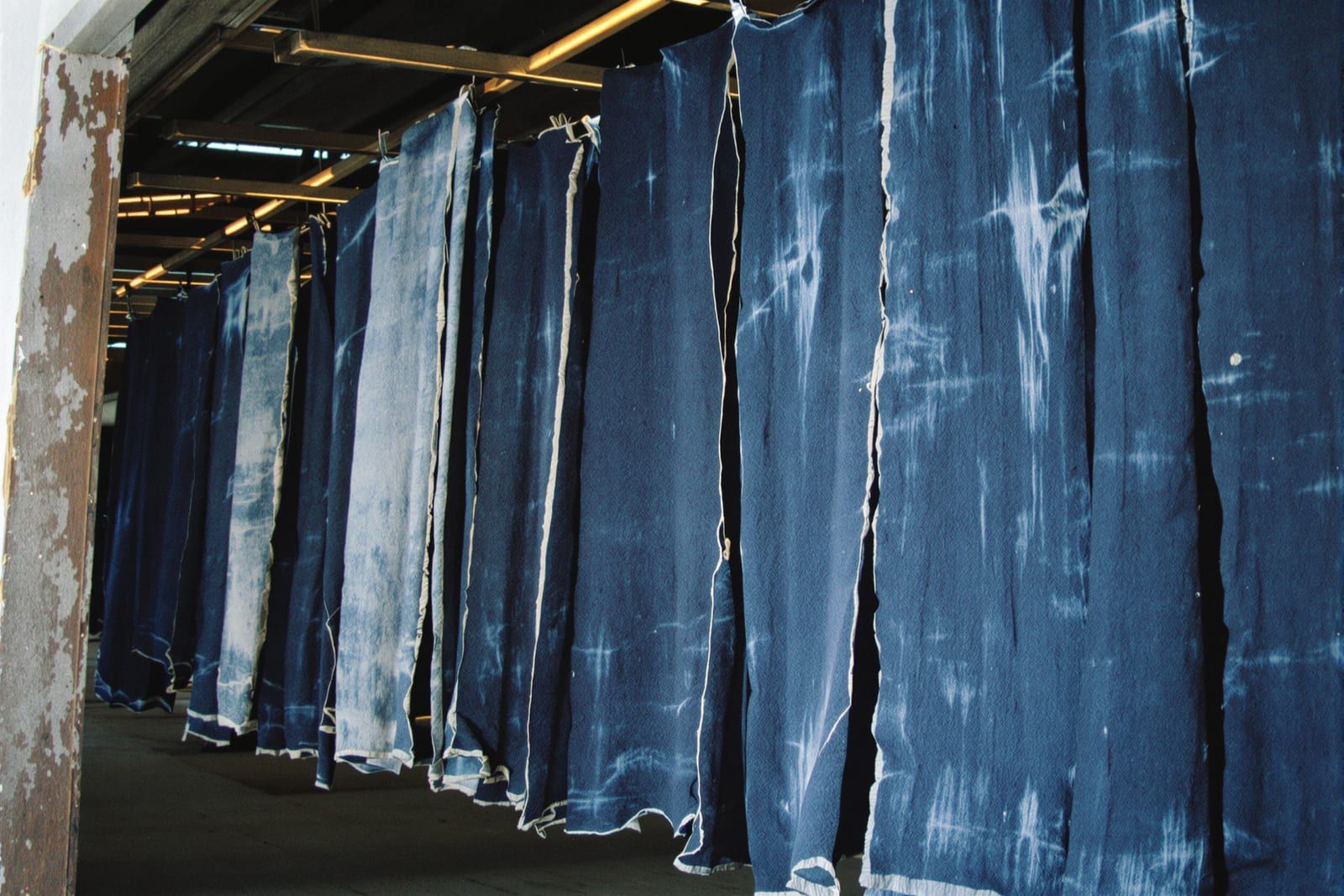 Lengths of indigo-dyed cotton cloth hanging to dry in a barn doorway