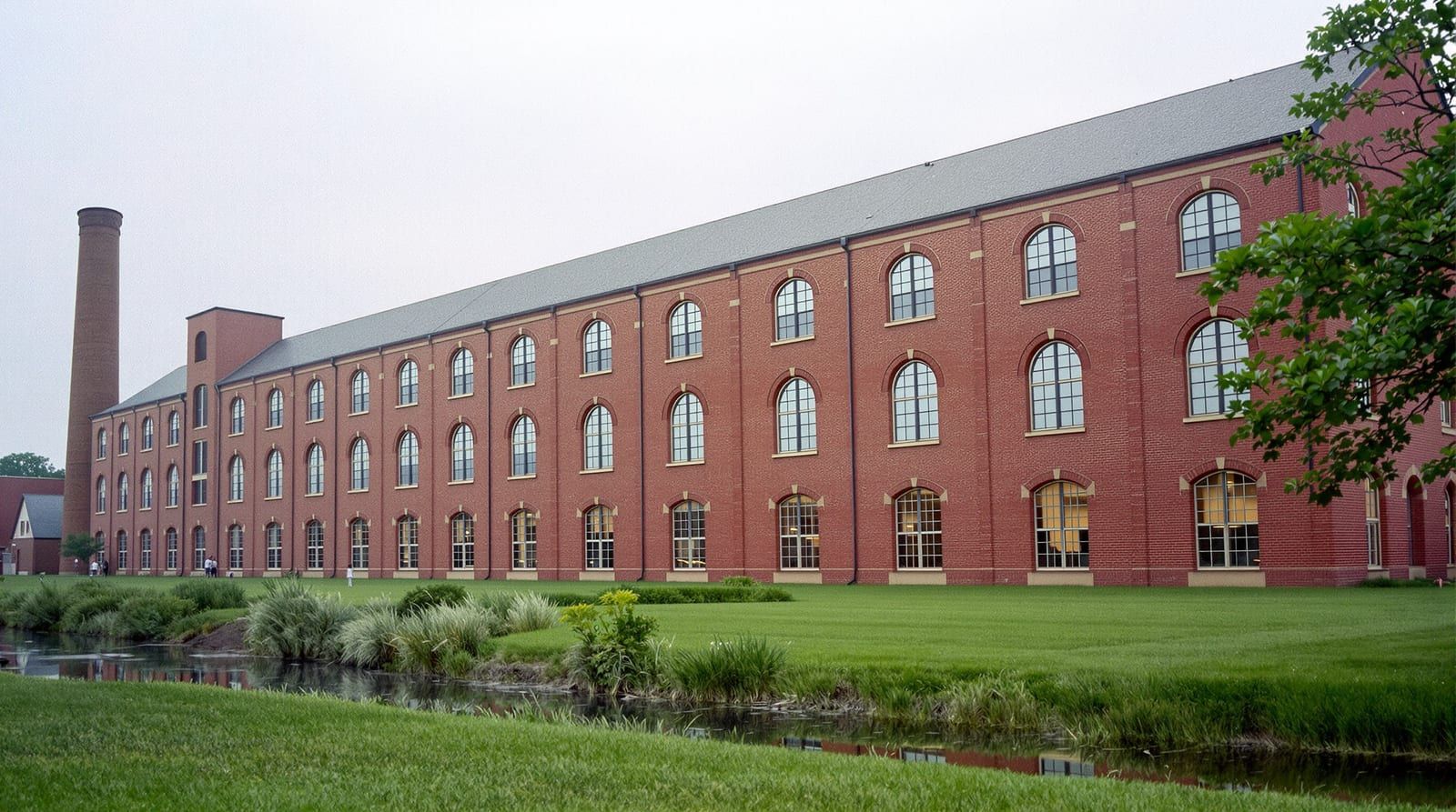 A long red brick textile mill with rows of arched windows, restored as lofts